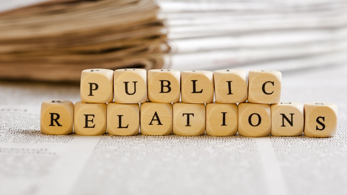 Public relations spelled using wooden blocks on top of newspapers
