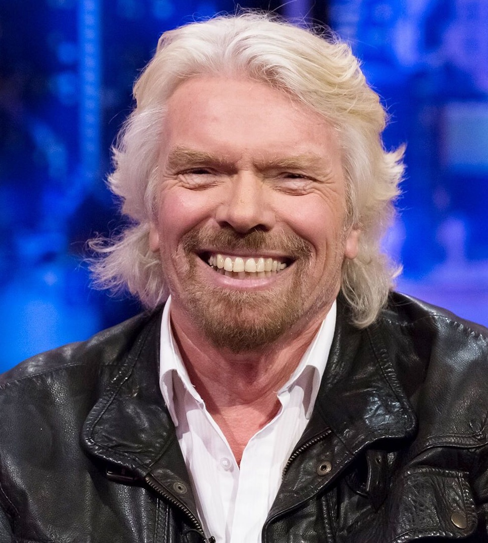 A blonde-hair man smiling wearing a black jacket