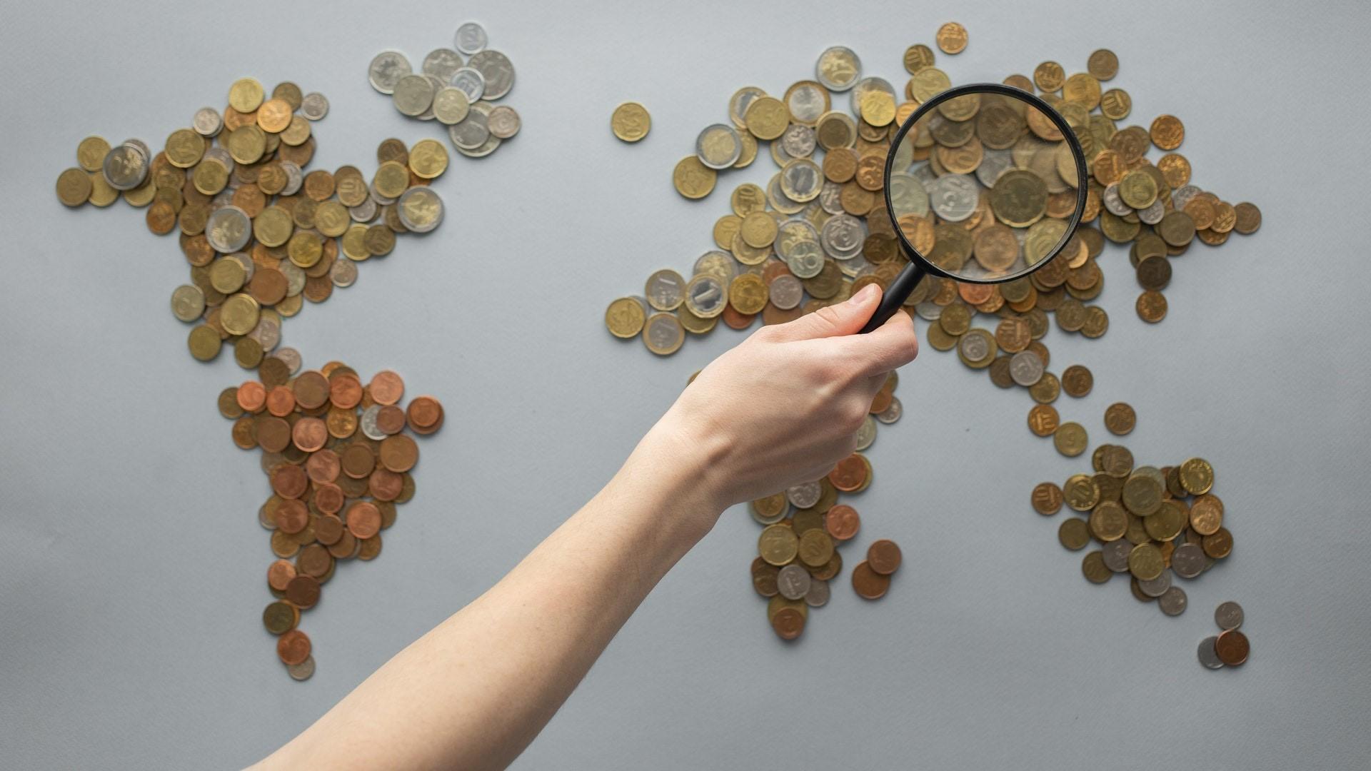 Coins and magnifying glass held by a hand