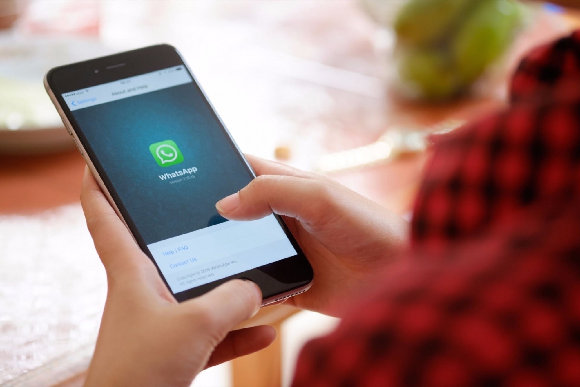 A hand using phone and whatsapp logo is on screen