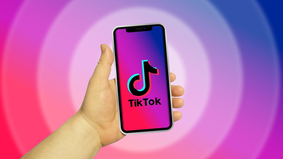 A hand holding a phone showing the TikTok logo on a colorful background
