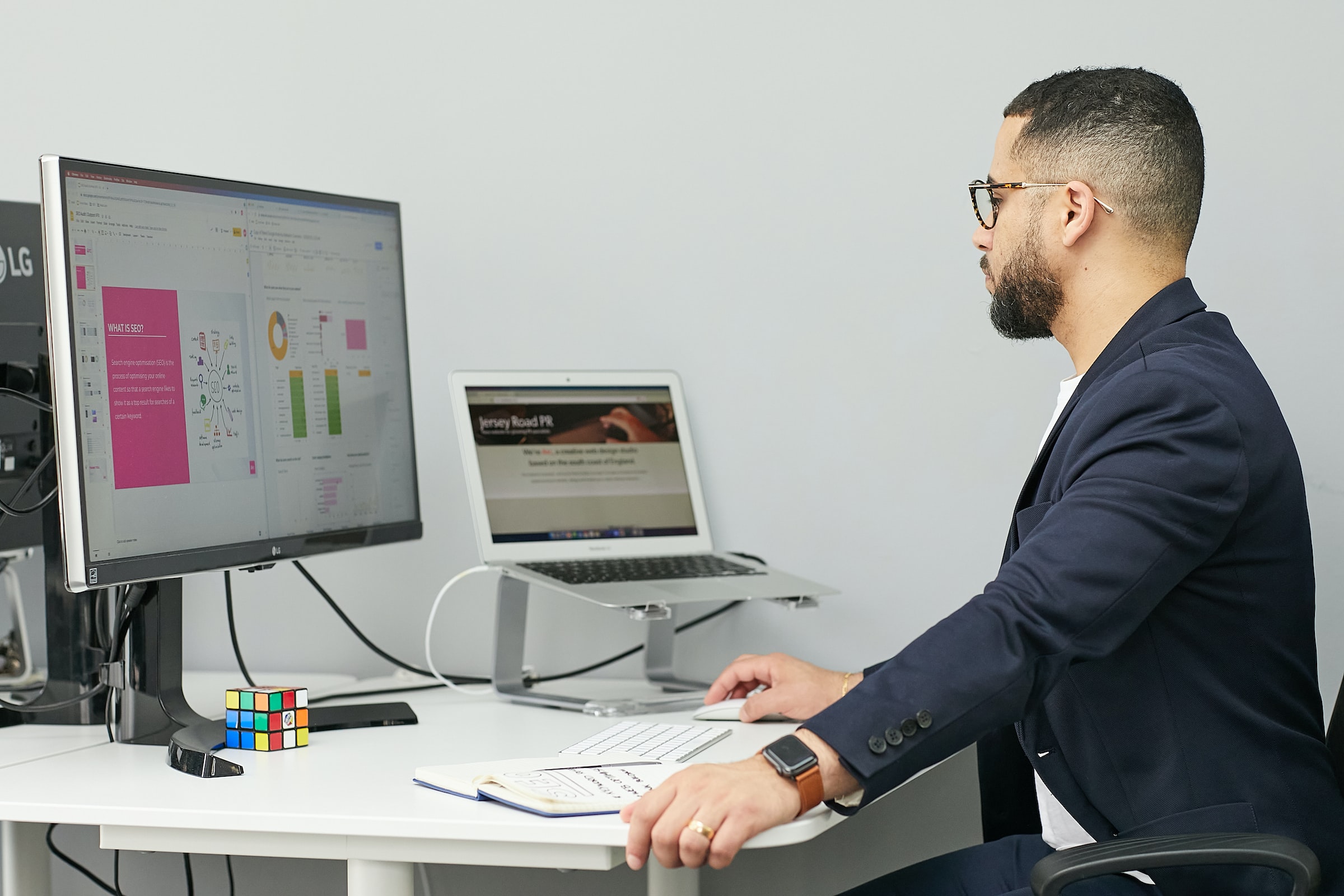 Man with a laptop and computer analysing metrics