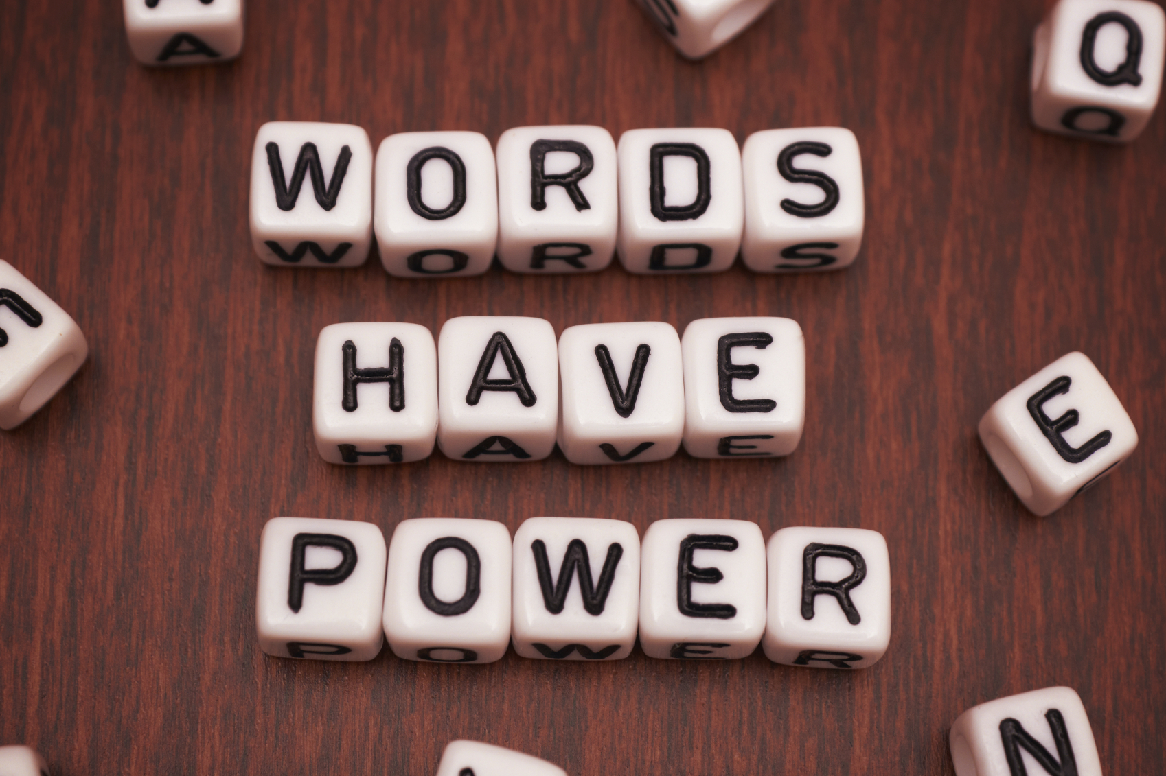 Dice with the phrase 'Words Have Power' on a wooden table