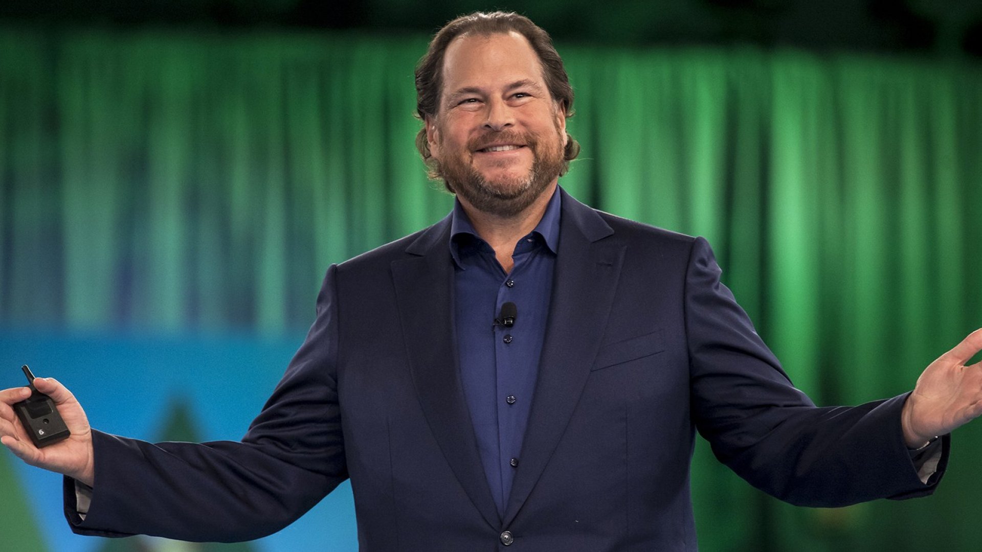 Smiling Marc Benioff wearing a blue suit while raising his arms