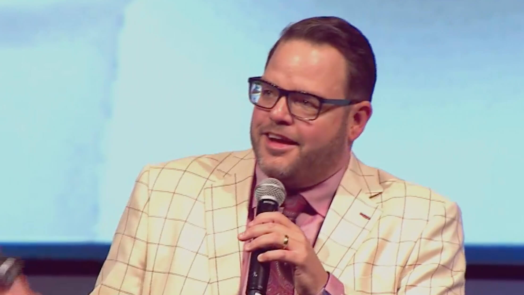Jay Baer wearing a yellow checkered coat while holding a mic