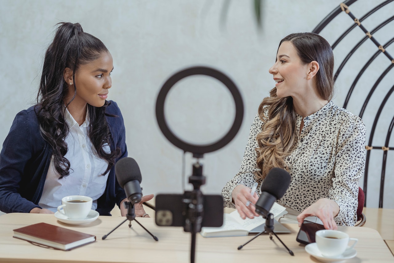 Two adult women seated and talking during an influencer marketing podcast