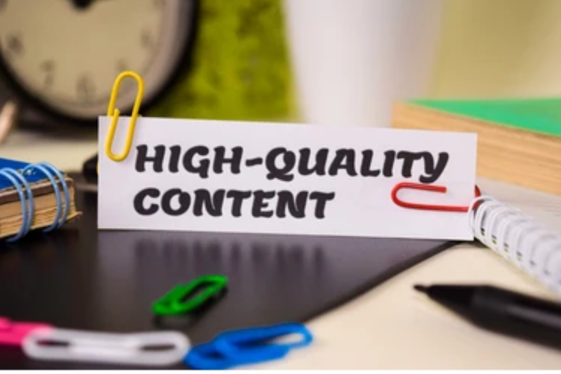 On top of a desk, a piece of paper with the words "High-quality content"