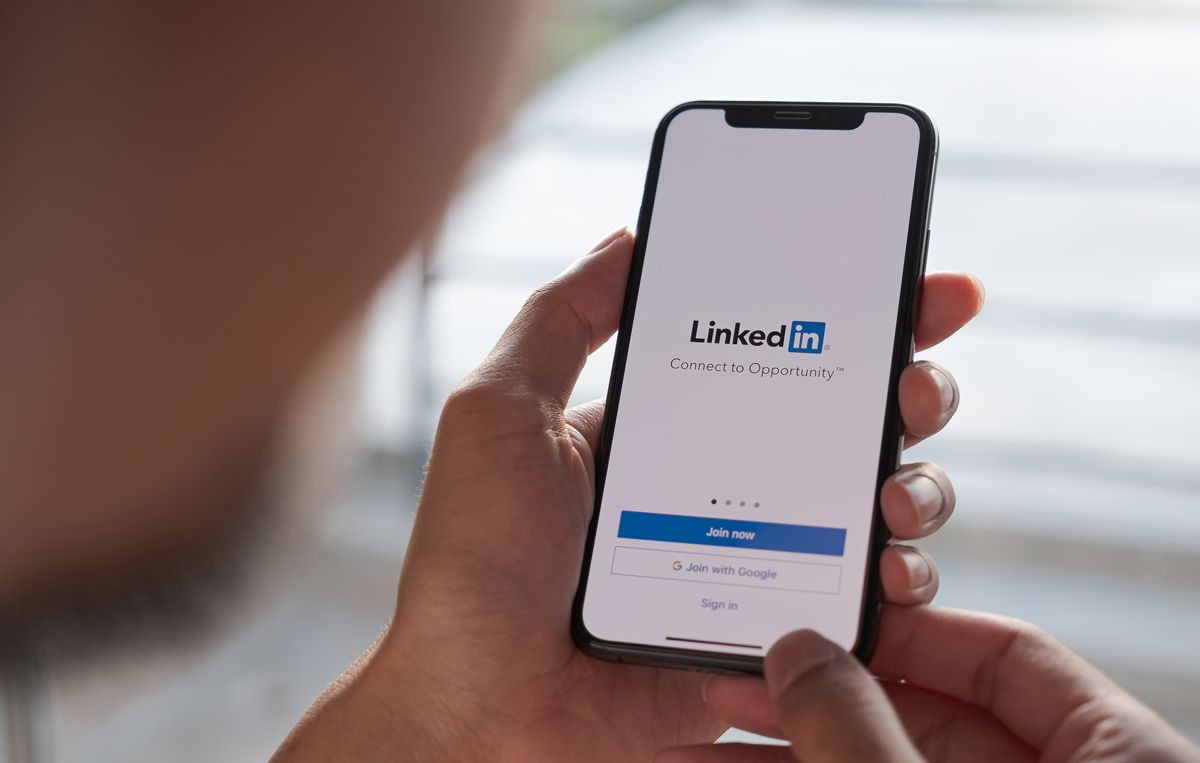 Hands holding a phone with a LinkedIn app