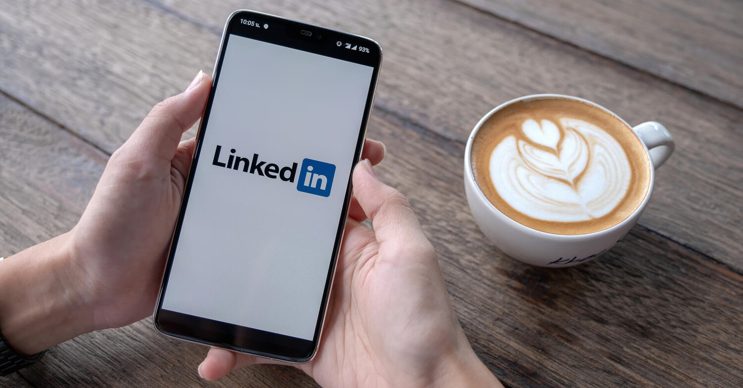 LinkedIn app on phone with cup of coffee on the table