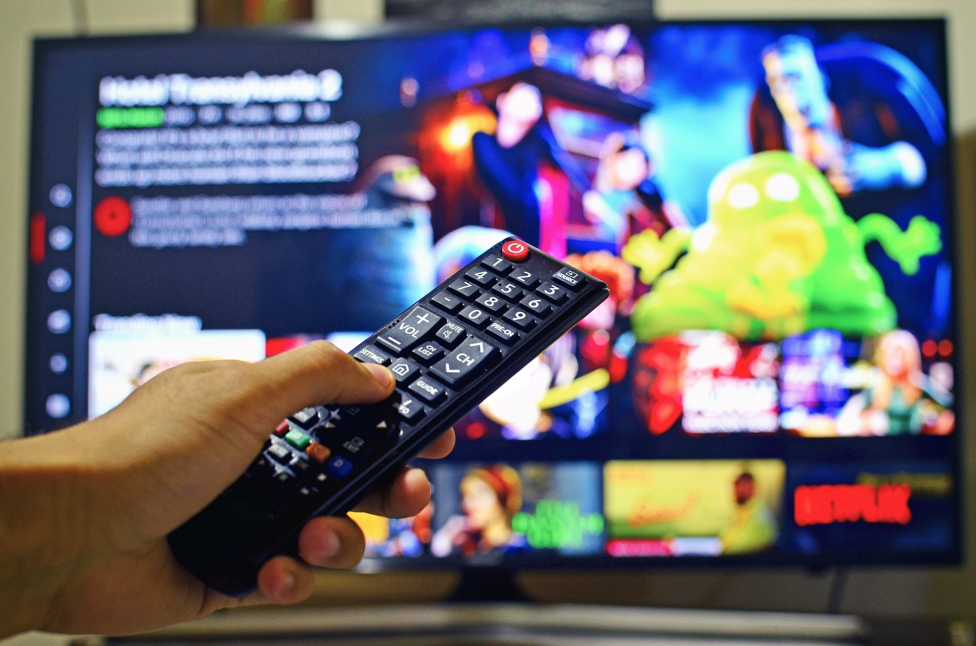 Hand holding a remote in front of a television