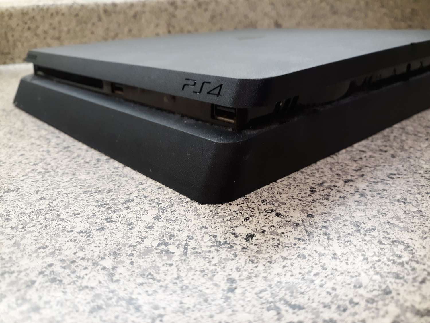 Black PS4 on a marble counter