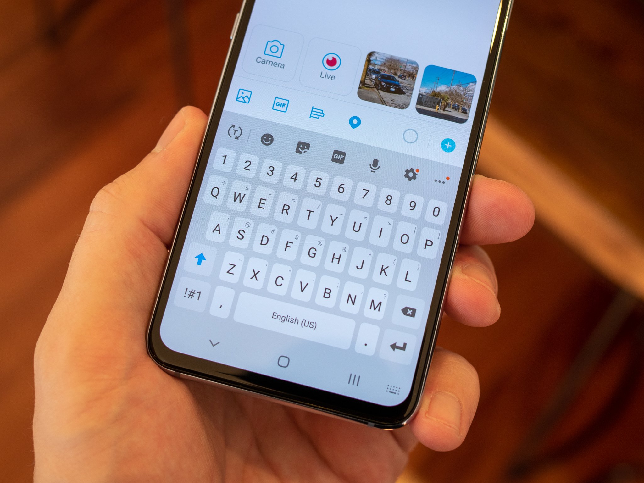 Hand holding a black samsung phone showing its keyboard on screen