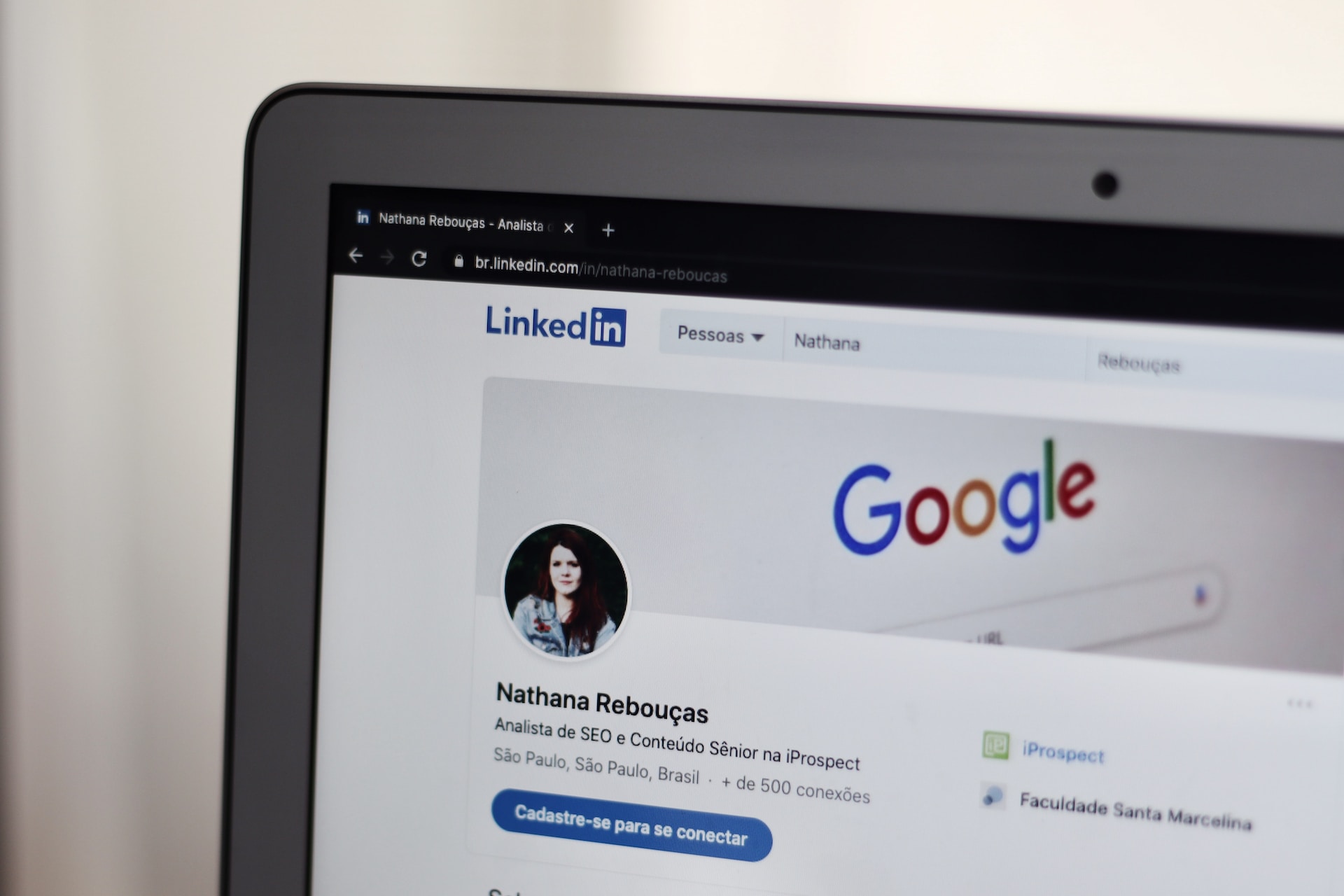 Upper right corner of a laptop showing a woman’s LinkedIn profile, with the Google homepage as cover picture