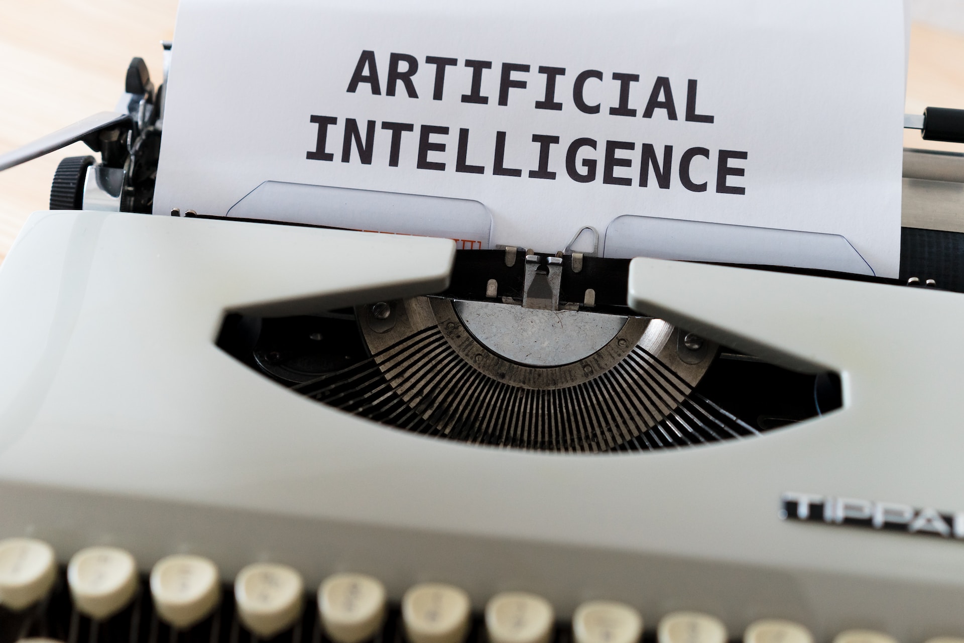 The words ‘artificial intelligence’ in uppercase letters in a bond paper inserted in a gray Tippa typewriter