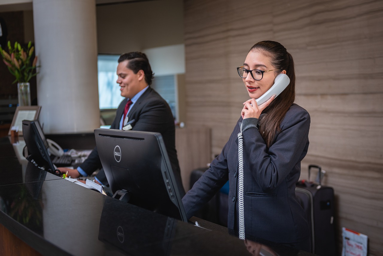Man receptionist smiling on his computer while woman receptionist is talking on a telephone