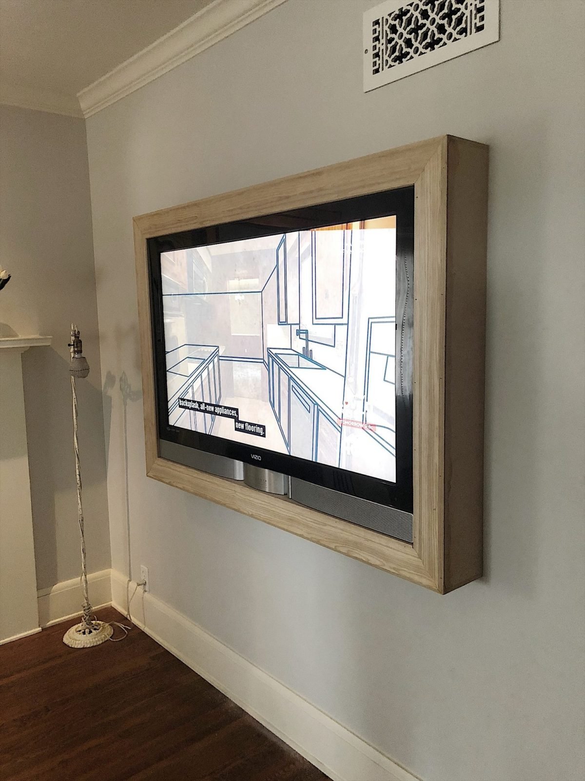 A TV mounted on a wall with a wooden frame