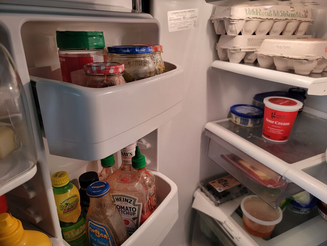 An open fridge with tray of eggs and condiments
