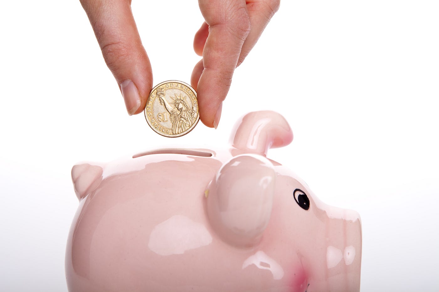 Hand putting a coin on a piggy bank