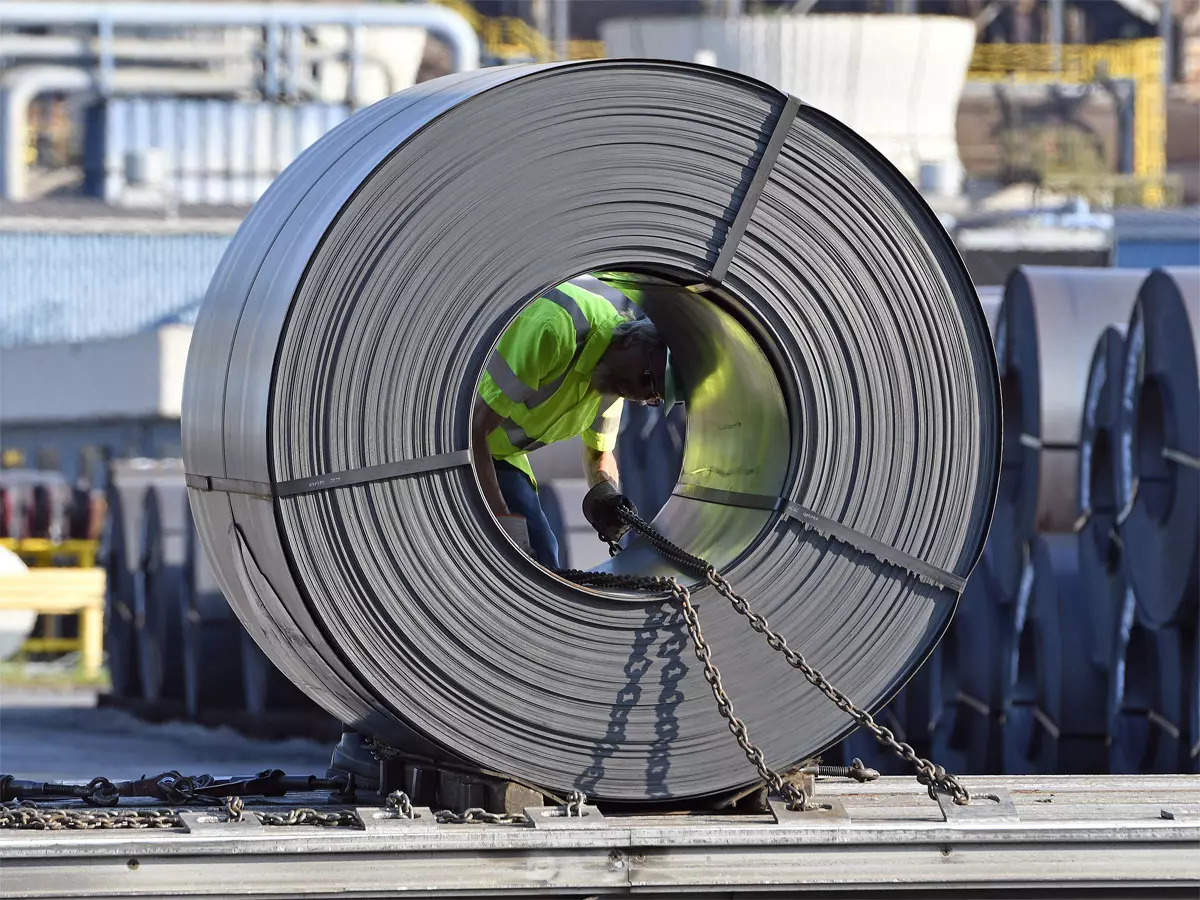A man in green vest looking at the steel roll
