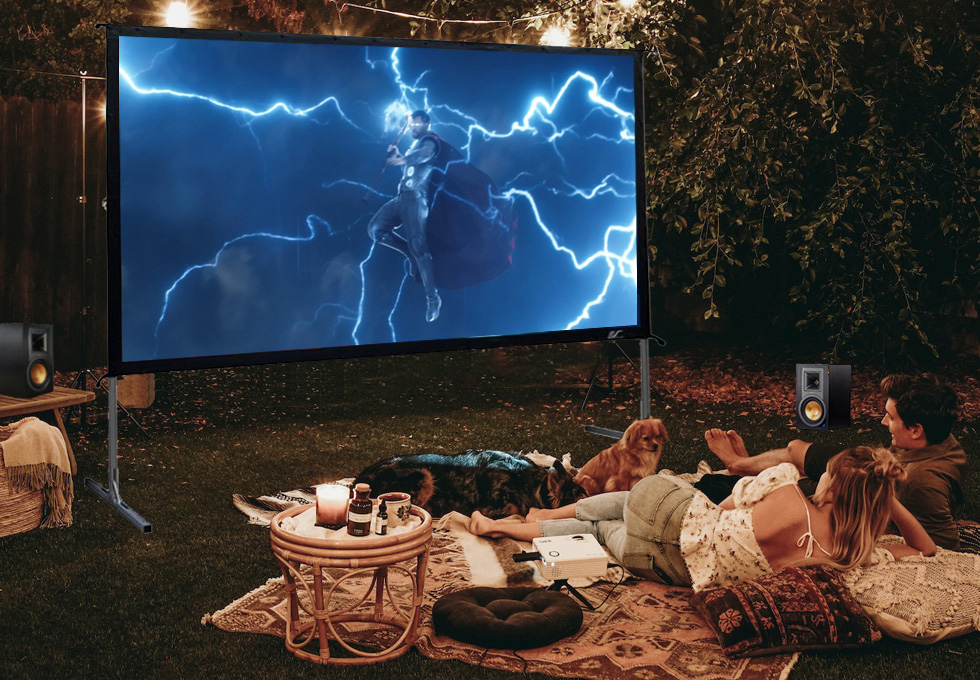 A couple having a movie night with their dogs in their backyard