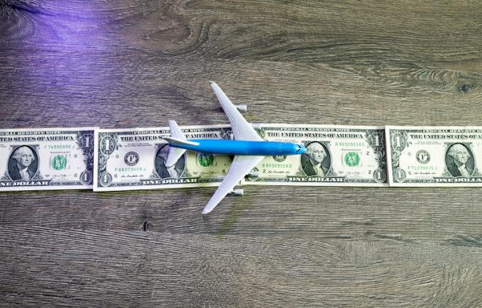 A toy airplane on a runway made of dollar bills. 