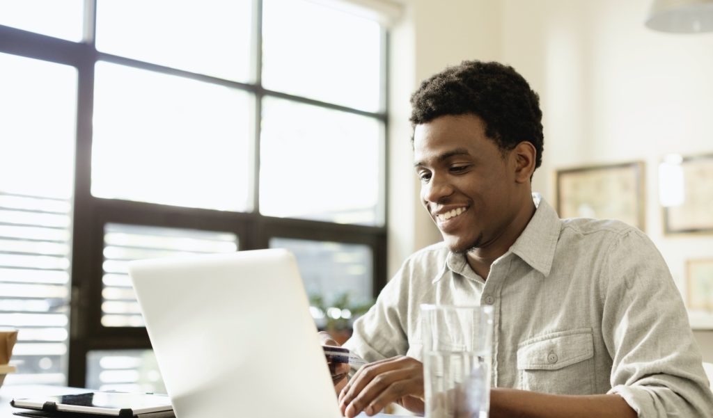 A man in white polo long sleeves in front of a laptop