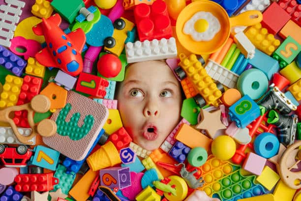 A kid's face surrounded by legos and other toys.