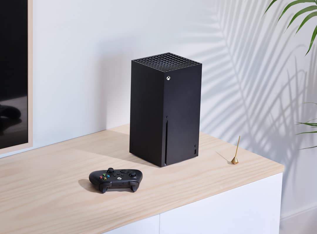 Black Xbox console and controller beside it on a table