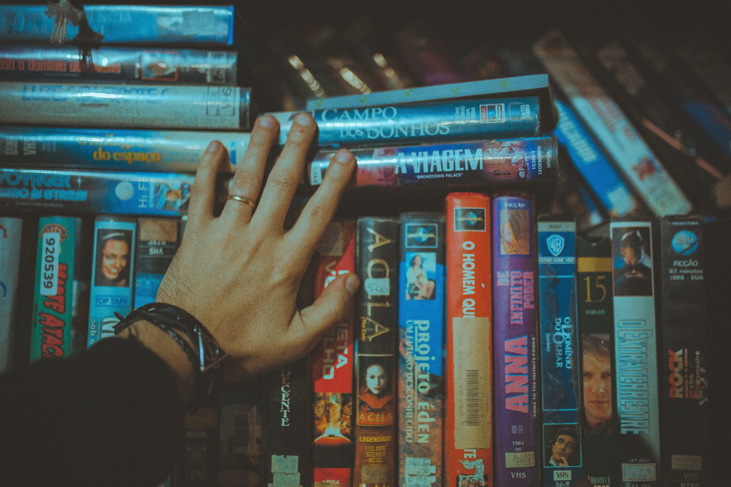 Hand holding VHS tapes on a shelf