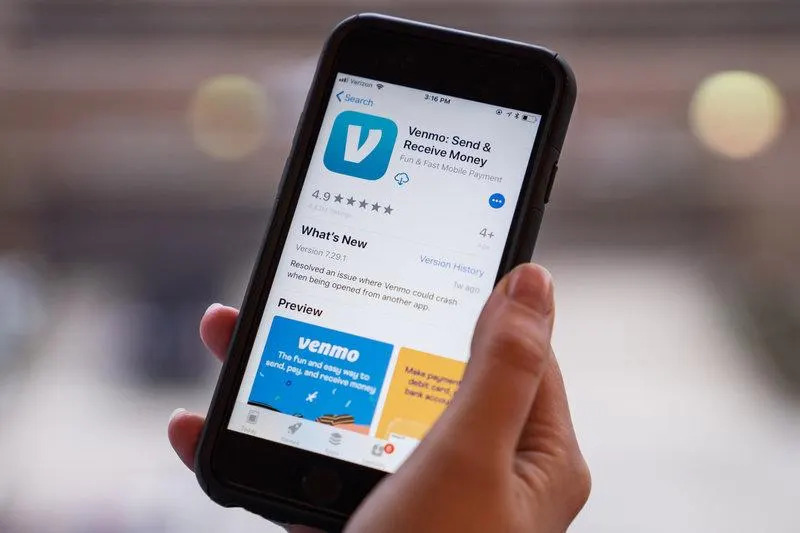 A hand holding a smartphone with the Venmo app on screen.