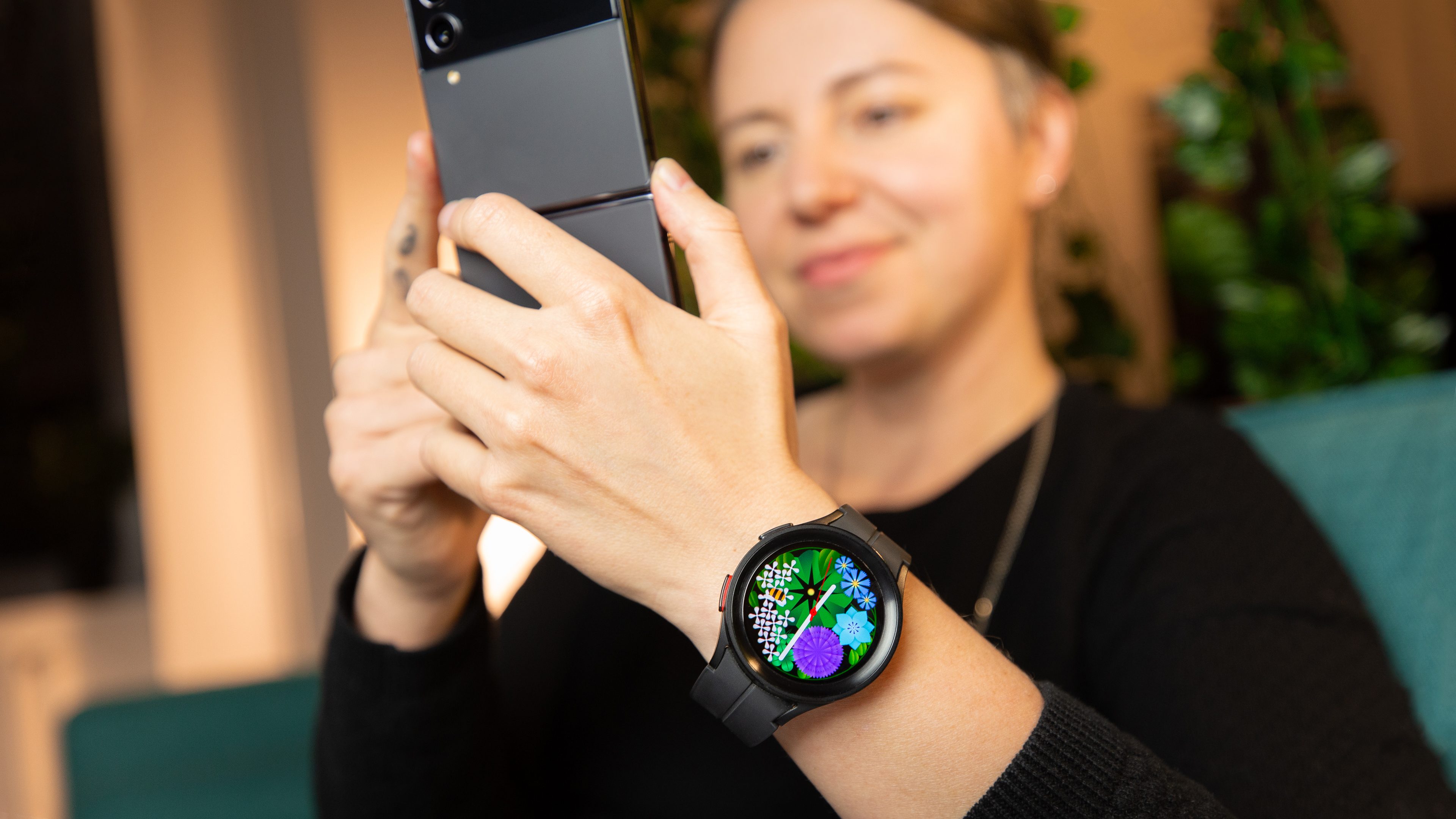 A woman holding a phone while wearing a Samsung Galaxy Watch