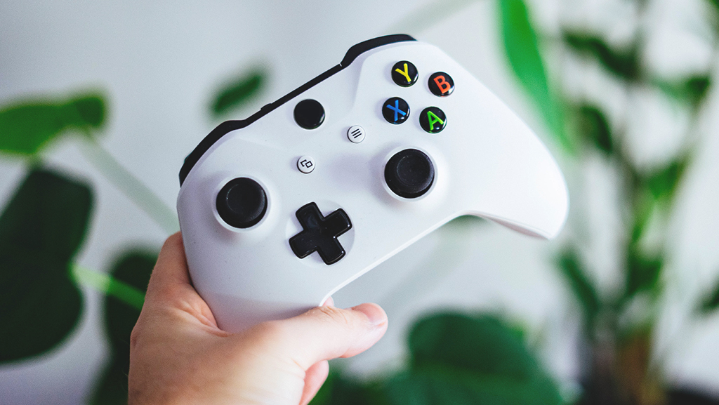 Hand holding a white Xbox One cotroller