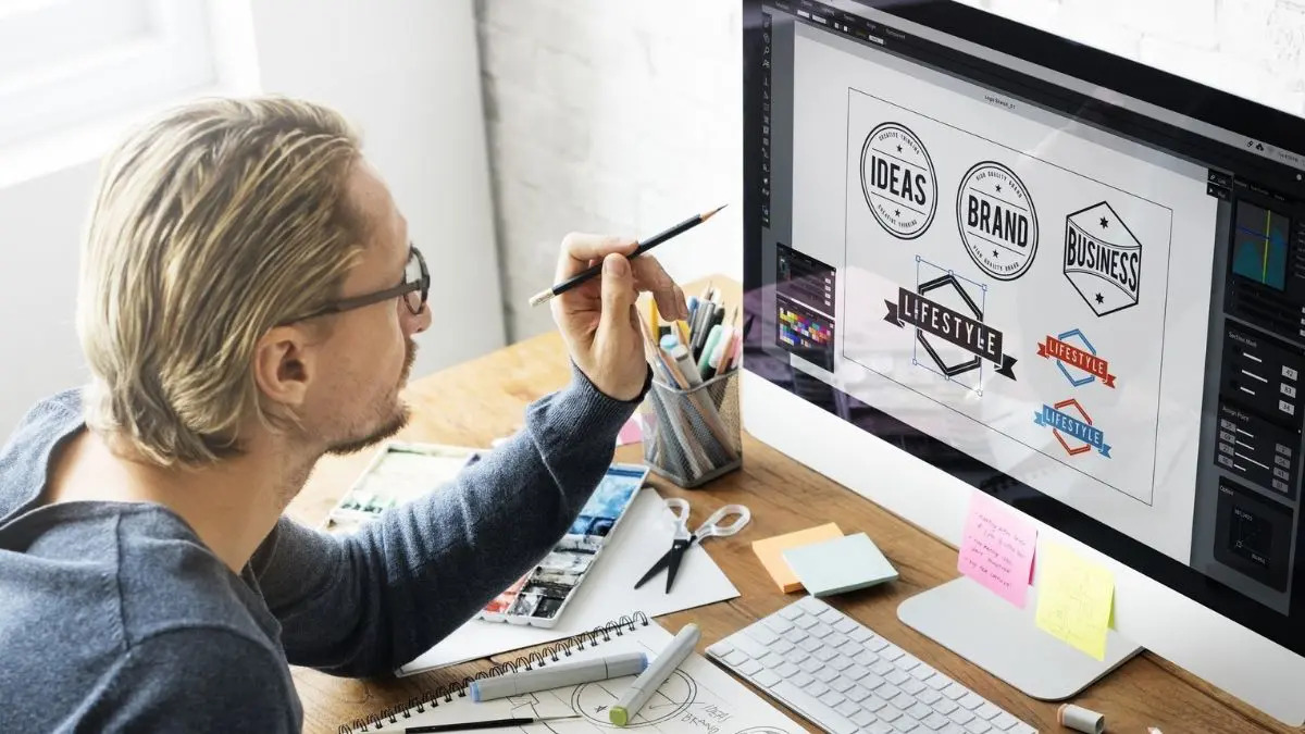 Man holding a pencil choosing logos from a computer screen.
