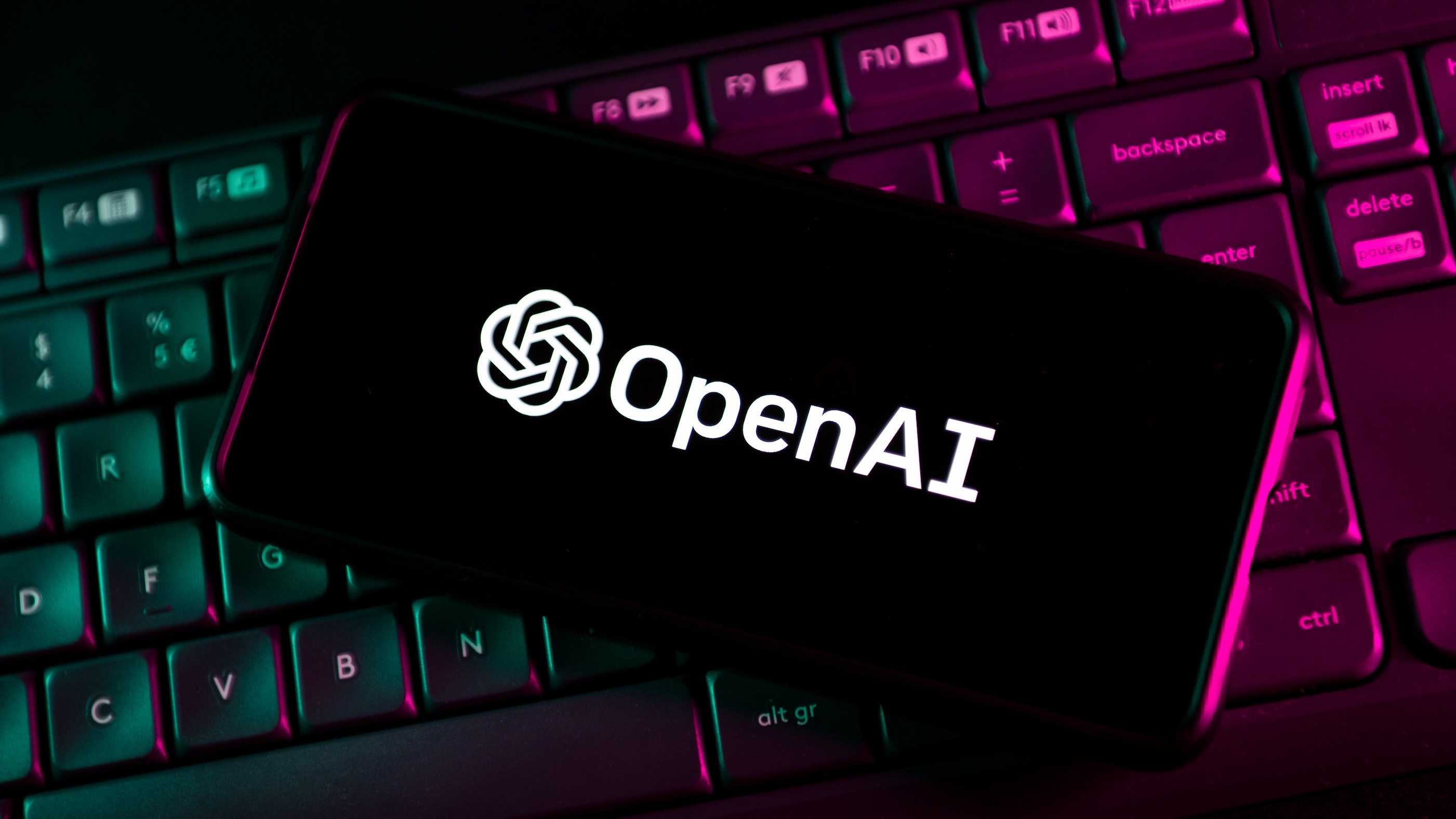 OpenAI and ChatGPT logo on a phone on top of a keyboard