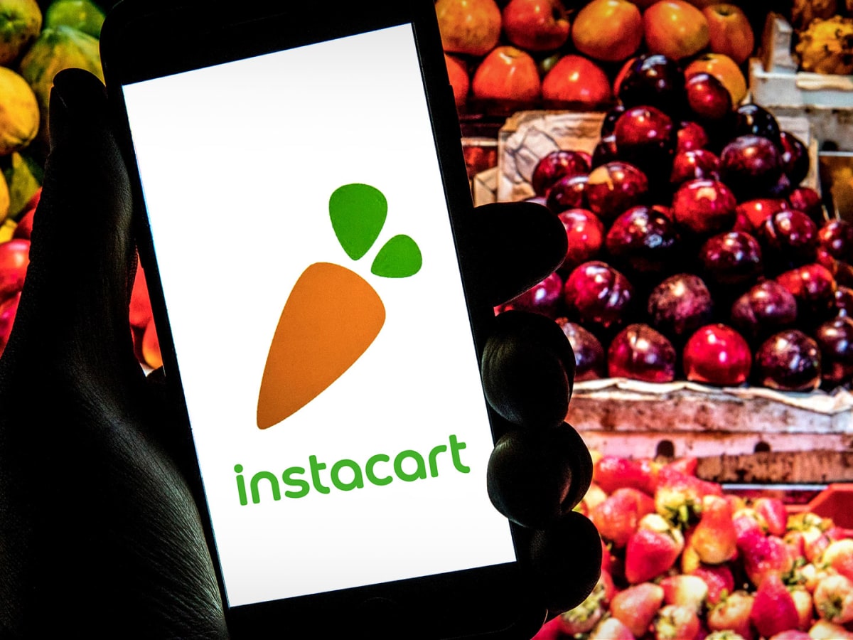 Instacart logo on a phone with fruits behind it