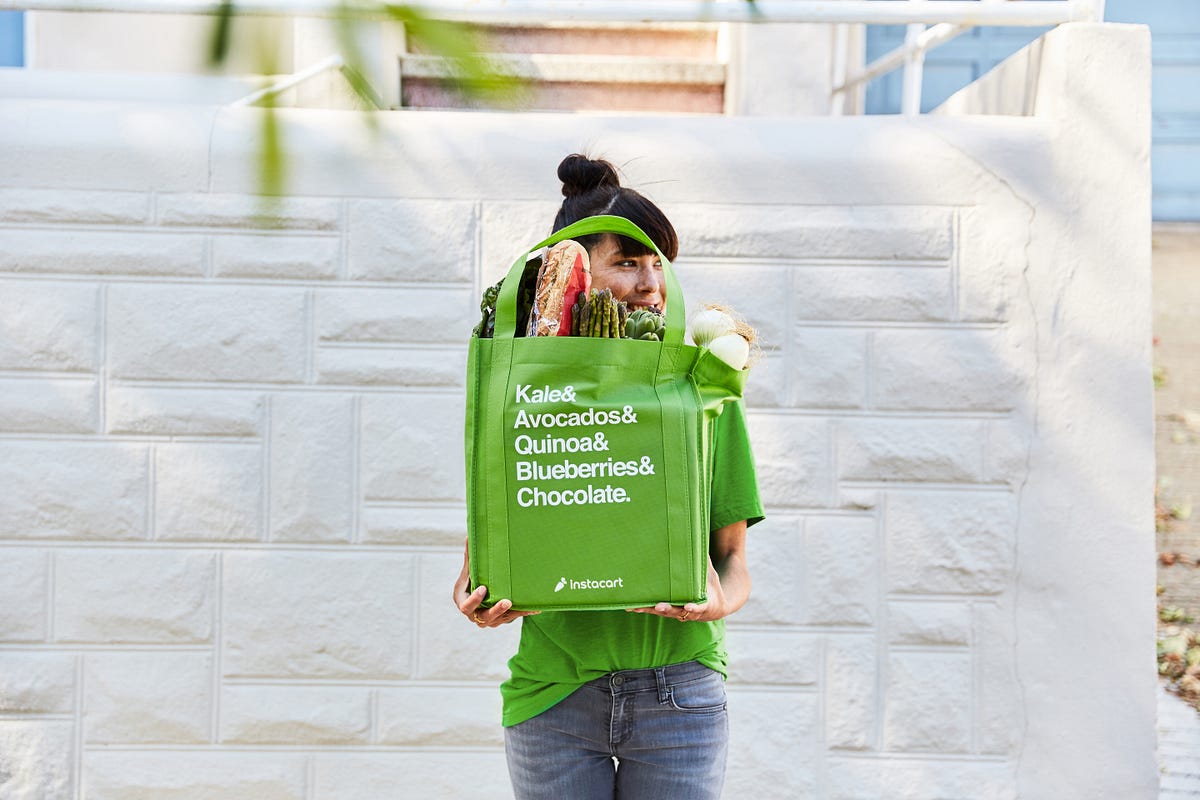 A woman holding a green grocery bag