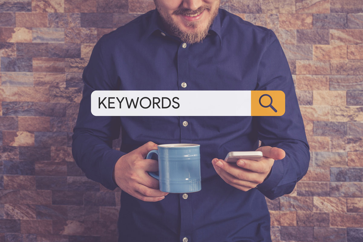 A man holding a phone with keywords on a search bar