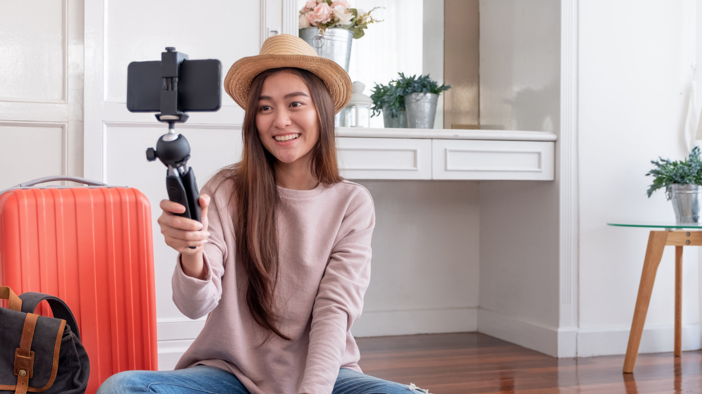A woman wearing a hat holding a tripod with phone