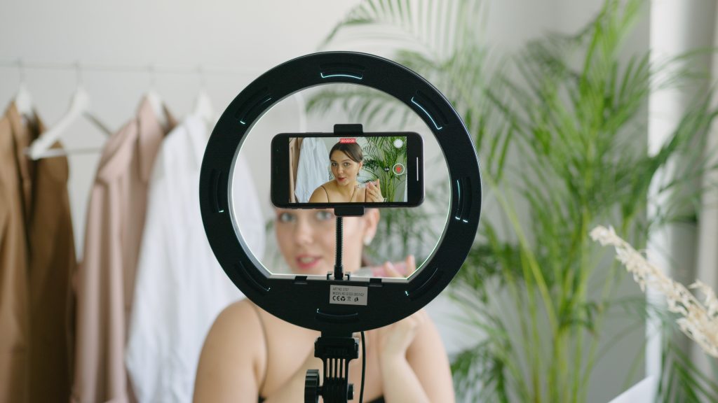 A woman recording in front of a phone and ring light