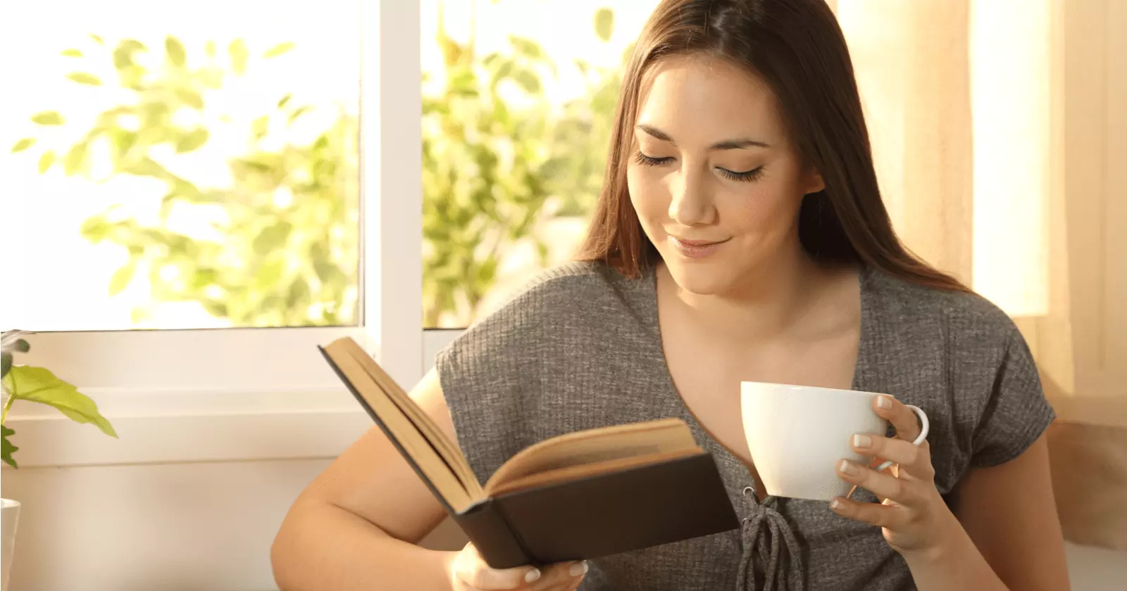A girl reading a book and drinking coffee