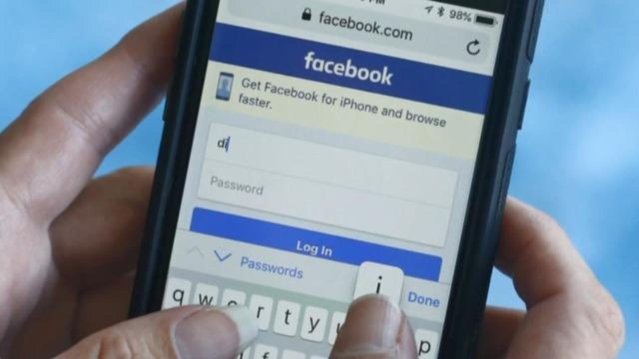 Hands typing on a phone Facebook application login