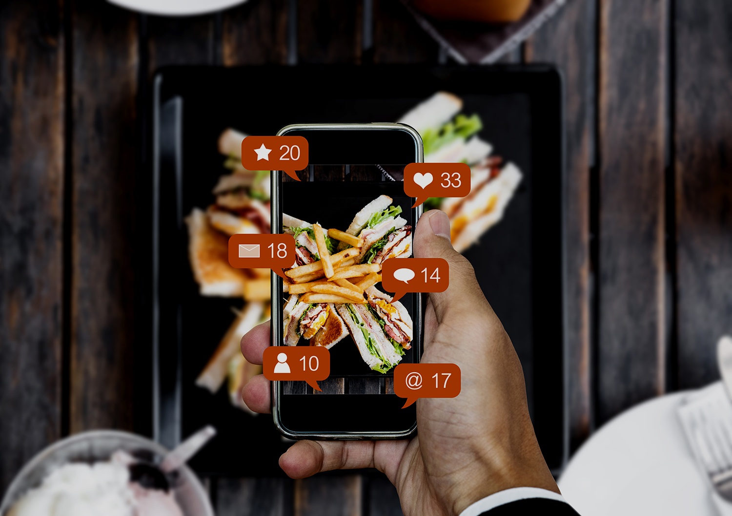 A hand holding a phone with image of food with notifications