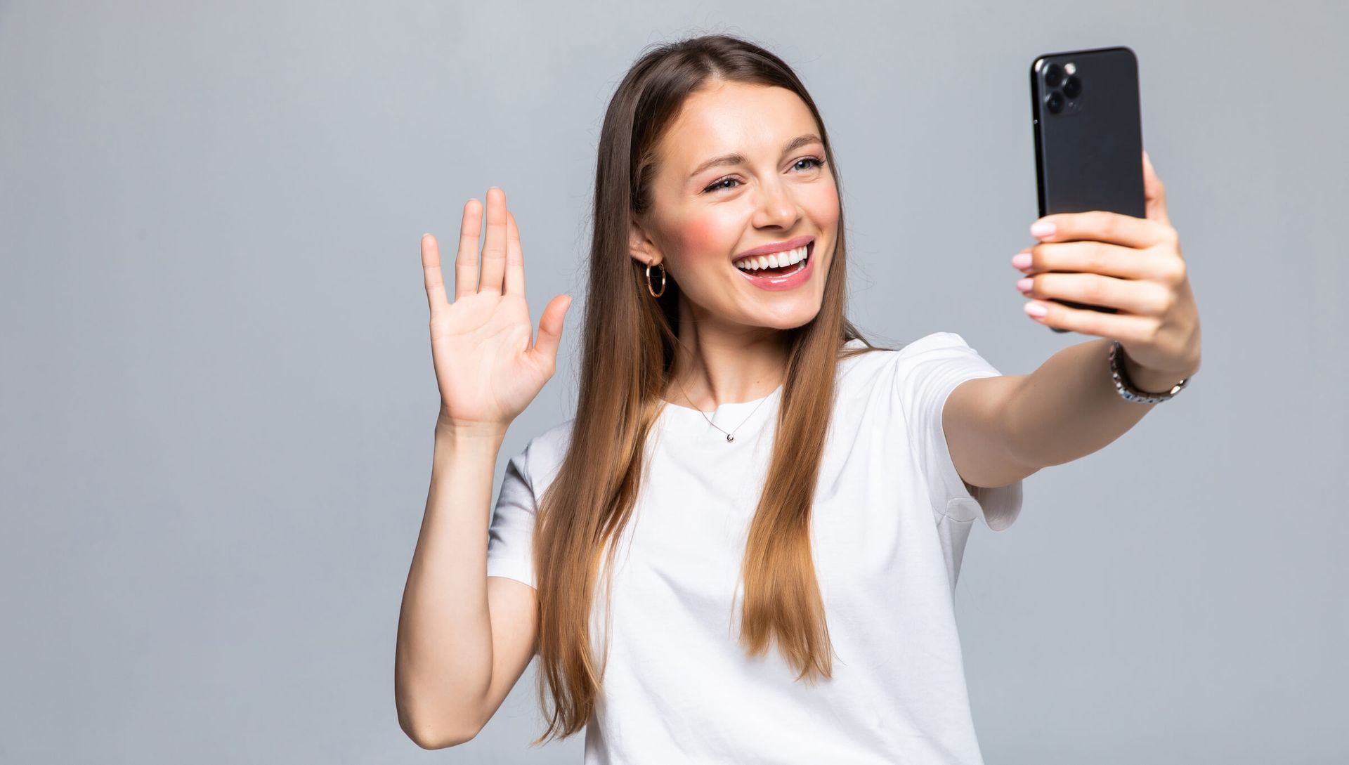 A woman waving on a phone while recording herself